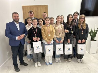 Wójt Radosław Nowakowski w towarzystwie mistrzyń w unihokeja ze Szkoły Podstawowej w Malechowie oraz dyrektor Piotr Chylarecki i trener Mariusz Małysz.