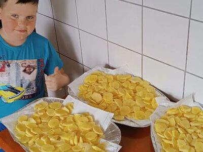 Chłopiec prezentuje pokrojone ziemniaki na chipsy.