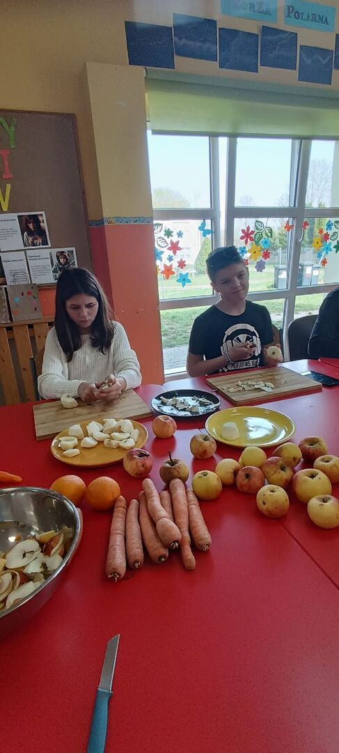 Wychowankowie obierają i kroją owoce i warzywa na sok.