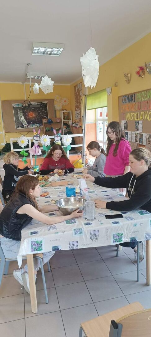 Dzieci obierają jabłka i przygotowują ciasto.