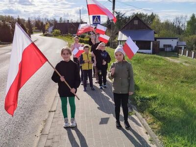 Przemarsz dzieci z flagami po ulicach miejscowości.