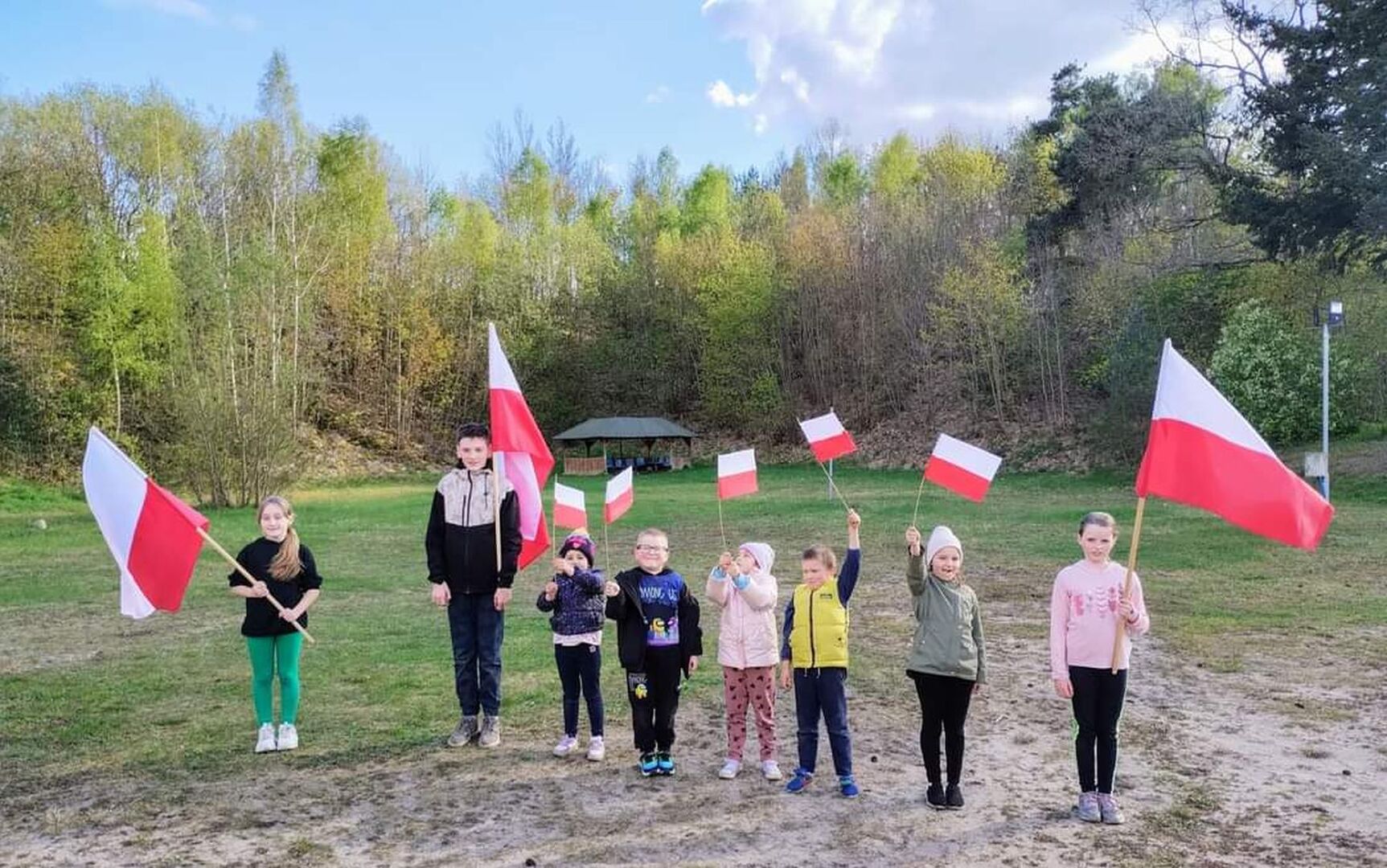 Dzieci pozują do zdjęcia z flagami Polski.