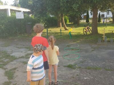 Dzieci w trakcie zabawy na świeżym powietrzu. Zabawa przy użyciu hula hop.