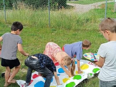Dzieci grają w twistera na świeżym powietrzu.