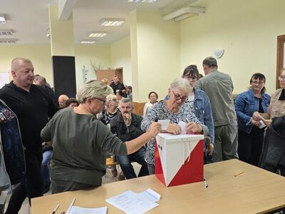 Uczestnicy zebrania wiejskiego na świetlicy w Karwicach wrzucają karty głosowania do urny wyborczej.