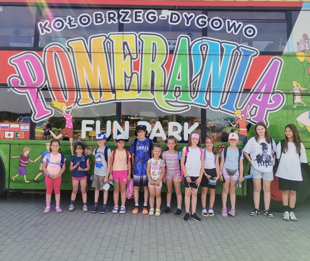 Pamiątkowe zdjęcie wychowanków PWD Sulechowo przy kolorowym autobusie w Parku Rozrywki.