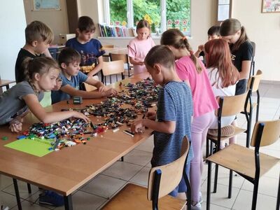 Zdjęcia przedstawiają dzieci układające klocki Lego.