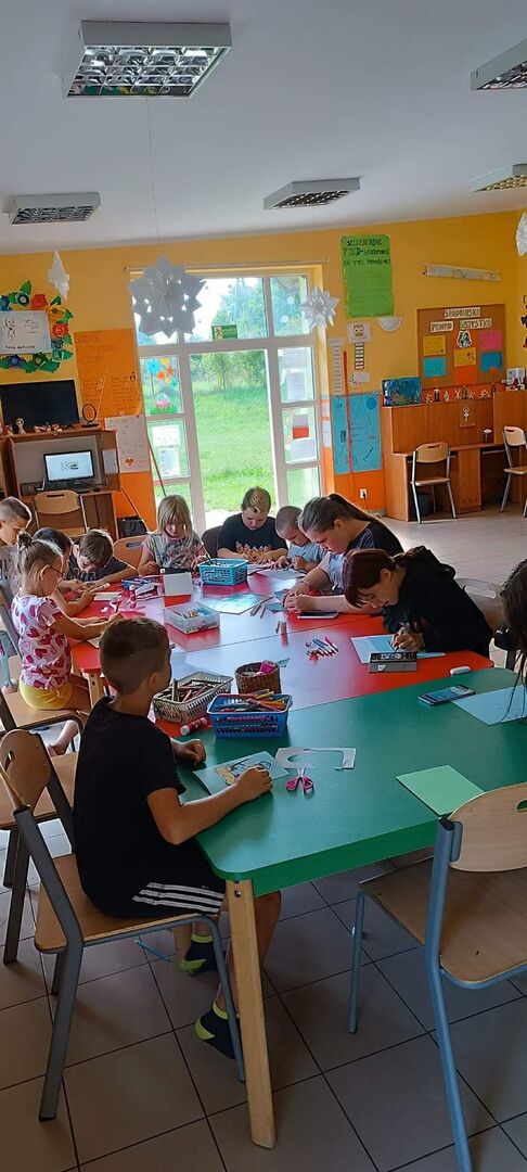 Dzieci wykonują laurki dla policjanta.