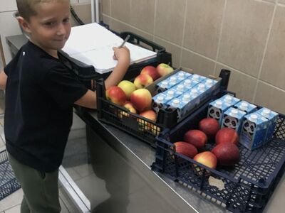 Julek z pierwszej klasy podpisuje odbiór przekąsek.