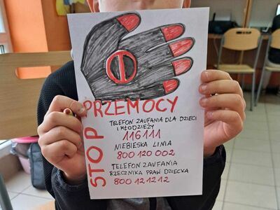 Chłopiec prezentuje wykonaną ulotkę.