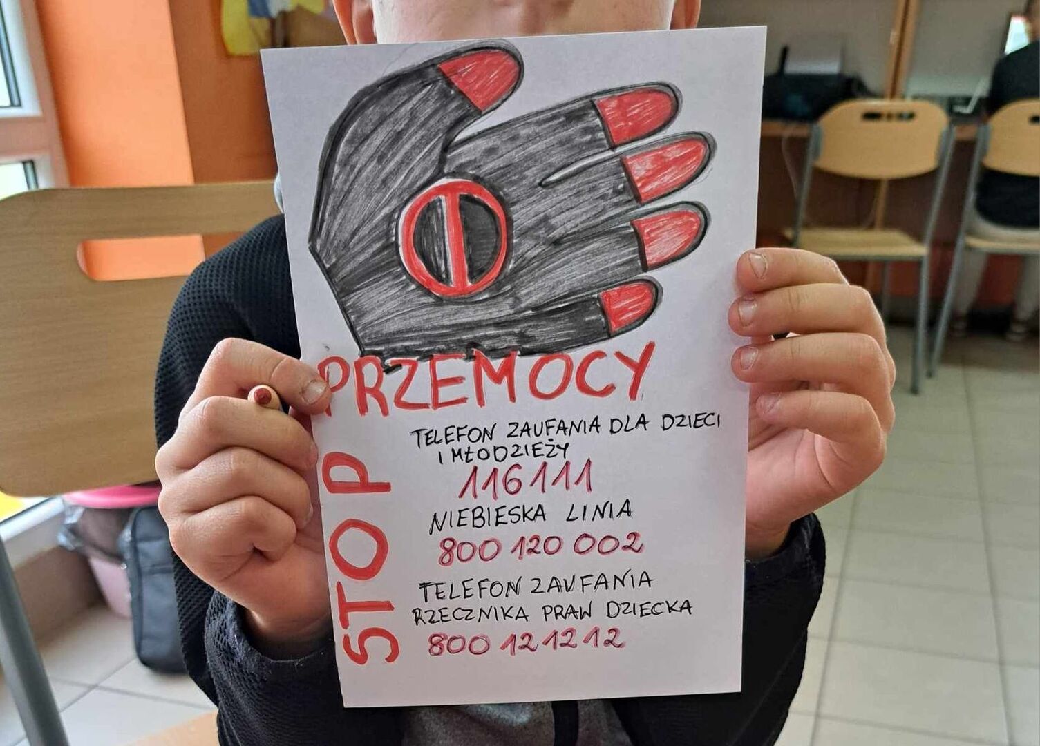 Chłopiec prezentuje wykonaną ulotkę.
