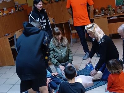 Ratownik kwalifikowanej pierwszej pomocy uczy dzieci wykonywania czynności udzielania pierwszej pomocy.