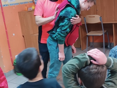 Ratownik kwalifikowanej pierwszej pomocy uczy dzieci wykonywania czynności udzielania pierwszej pomocy.