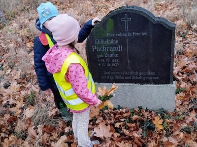 Dzieci stojące przy nagrobku na poniemieckim cmentarzu