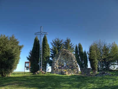 Widok Pola zjawienia wraz z murowaną kapliczką i metalowym krzyżem