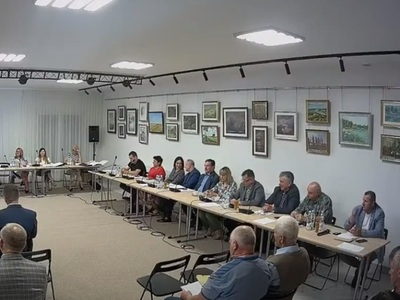 Zdjęcia przedstawiające obrady sesji. Przedstawia osoby siedzące za stolami obrad.