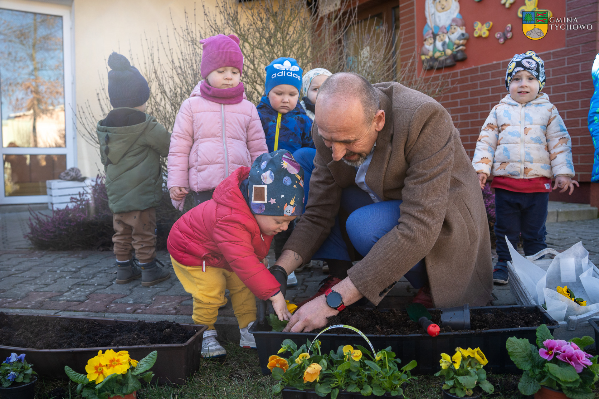 Na zdjęciu Zastępca Burmistrza Tychowa Jacek Marcinkowski pomaga sadzić maluszką ze złobka kwiaty.
