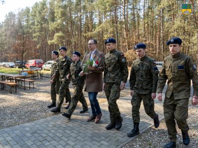 Na zdjęciu Dyrektor Liceum Ogólnokształcącego wraz z uczniami składa kwiaty pod pomnikiem Obozy Stalag Luft IV.