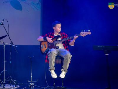 Zdjęcie wykonano podczas koncertu z okazji Dnia Matki w Gminnym Ośrodku Kultury w Tychowie - chłopiec gra na gitarze.