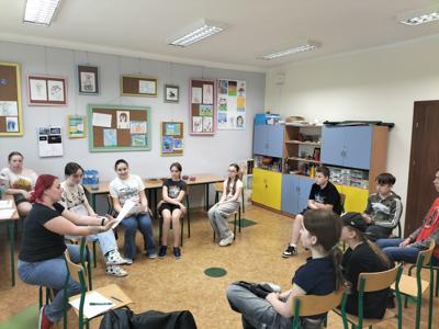 Pierwsze spotkanie z młodzieżą chcącą uczestniczyć w projekcie. Młodzież siedzi na krzesełkach w sali plastycznej i rozmawiają o przebiegu projektu z koordynatorką projektu.