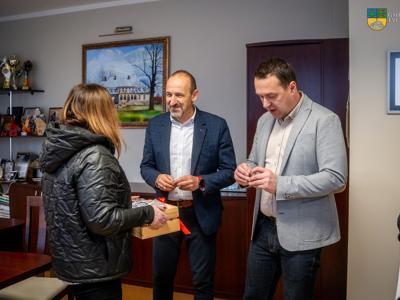 Kierownik Gminnego Ośrodka Pomocy Społecznej w Tychowie wręcza Burmiastrzowi oraz Zastępcy Burmistrza butony.