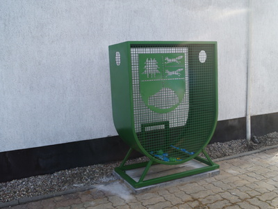 Na zdjęciu pojemnik zielony na plastikowe nakrętki w kształcie herbu Gminy Tychowo zamontowany przy UM w Tychowie