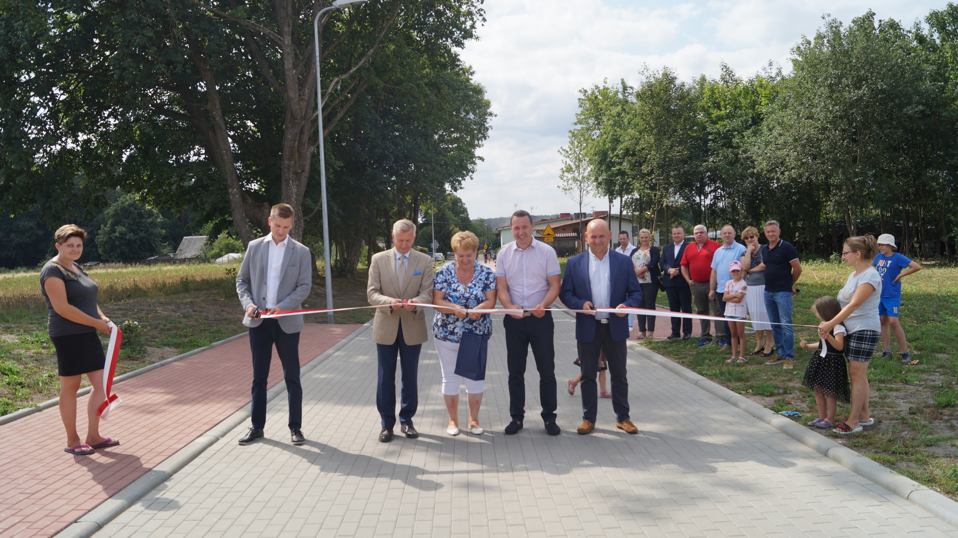 Symboliczne przecięcie wstęgi podczas uroczystego oddania do użytku drogi gminnej w Liśnicy.