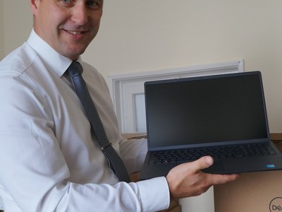 Burmistrz Tychowa Robert Falana trzyma w rękach laptopa.