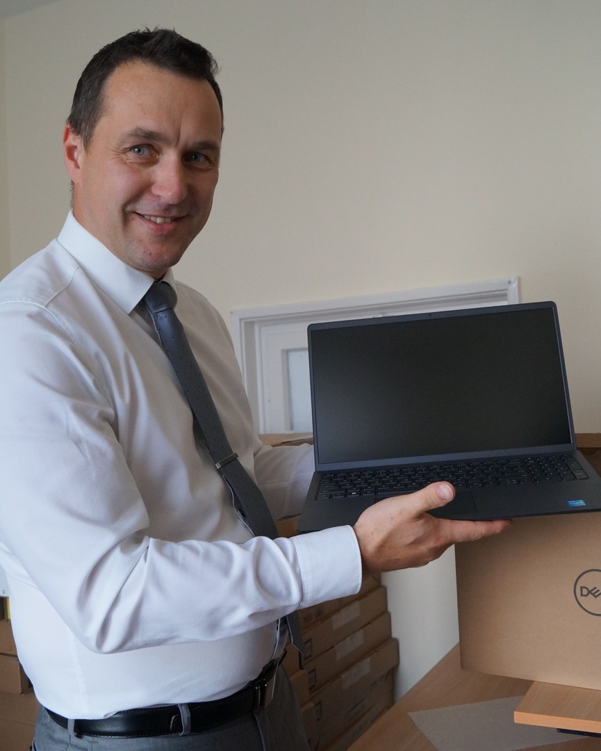 Burmistrz Tychowa Robert Falana trzyma w rękach laptopa.