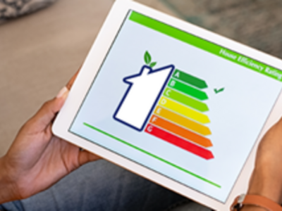 Na zdjęciu widać tablet ze szkicem domu wraz z wskaźnikami efektywności energetycznej.