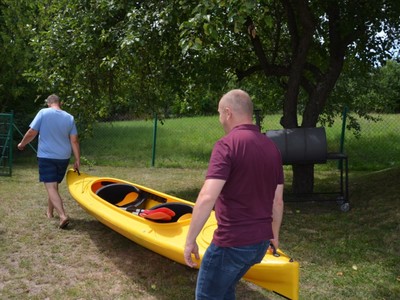 Przygotowanie do nagrania. Panowie niosą kajak