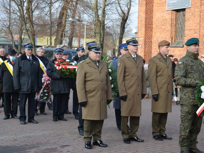 Przedstawiciele służb mundurowych składają wieniec przed obeliskiem na Placu Wolności