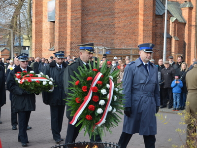 Przedstawiciele służb mundurowych składają wieniec przed obeliskiem na Placu Wolności