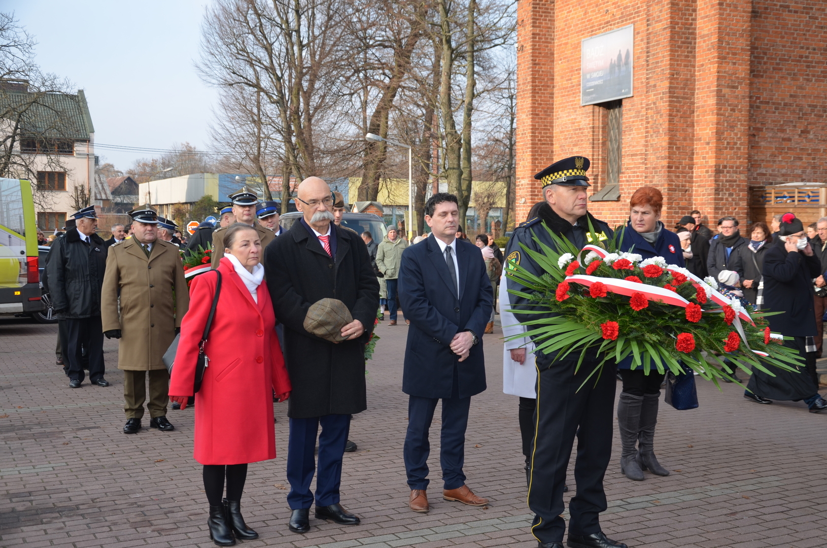 Przedstawiciele lokalnych władz samorządowych składają wieniec przed obeliskiem na Placu Wolności