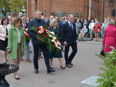 Dyrektorzy szkół ponadpodstawowych składają kwiaty przed pomnikiem 
